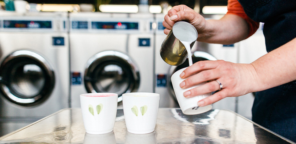A customer at the Coin Clean Laundry pouring cream into a cup of coffee